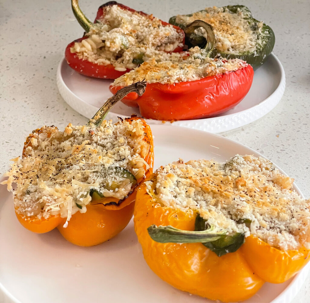 Stuffed peppers filled with cheese and topped with parmesan, beautifully arranged on a plate.