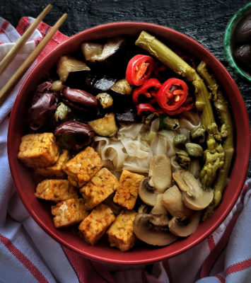 A bowl filled with fresh asparagus, sautéed mushrooms, and cubed tofu, showcasing a healthy, colorful dish.