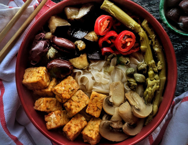 A bowl filled with fresh asparagus, sautéed mushrooms, and cubed tofu, showcasing a healthy, colorful dish.