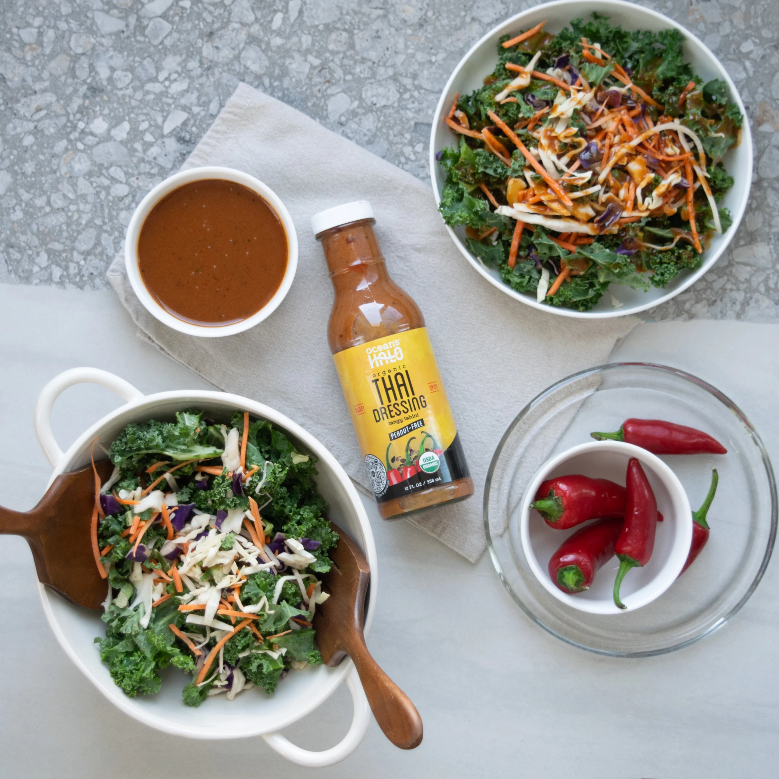 Fresh kale salad topped with shredded carrots alongside a bottle of Ocean's Halo Organic Thai Dressing.