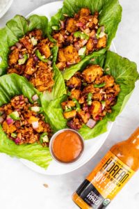 A plate of fresh lettuce wraps accompanied by a flavorful sauce and a small bowl of dipping sauce.