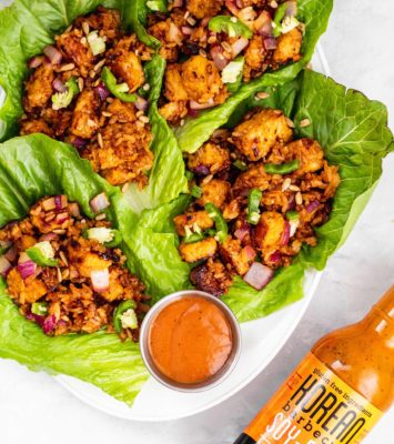 A plate of fresh lettuce wraps accompanied by a flavorful sauce and a small bowl of dipping sauce.