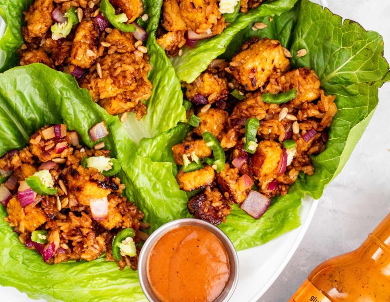 A plate of fresh lettuce wraps accompanied by a flavorful sauce and a small bowl of dipping sauce.