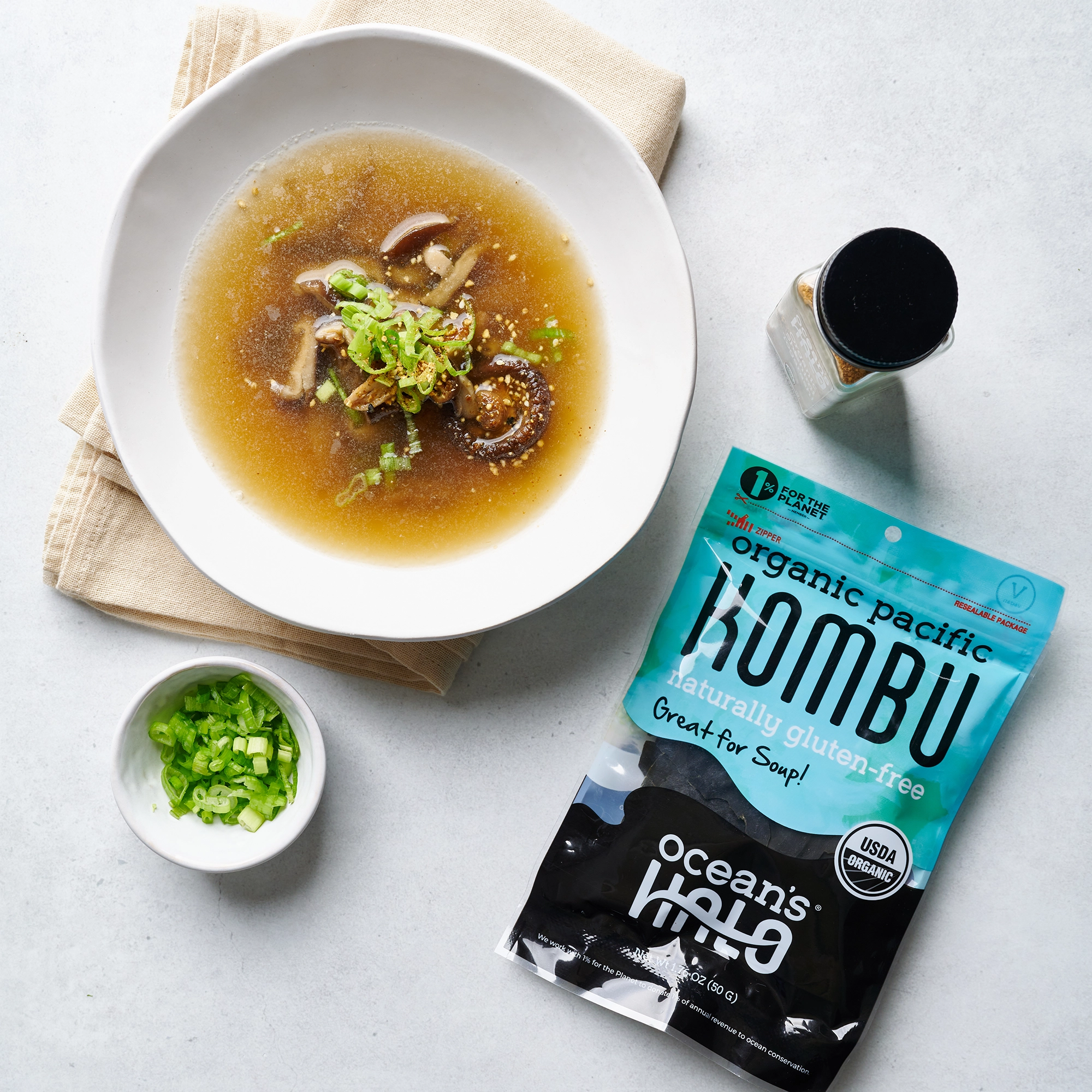 Bowl of broth topped with green onions and mushrooms next to an Ocean's Halo Organic Pacific Kombu package