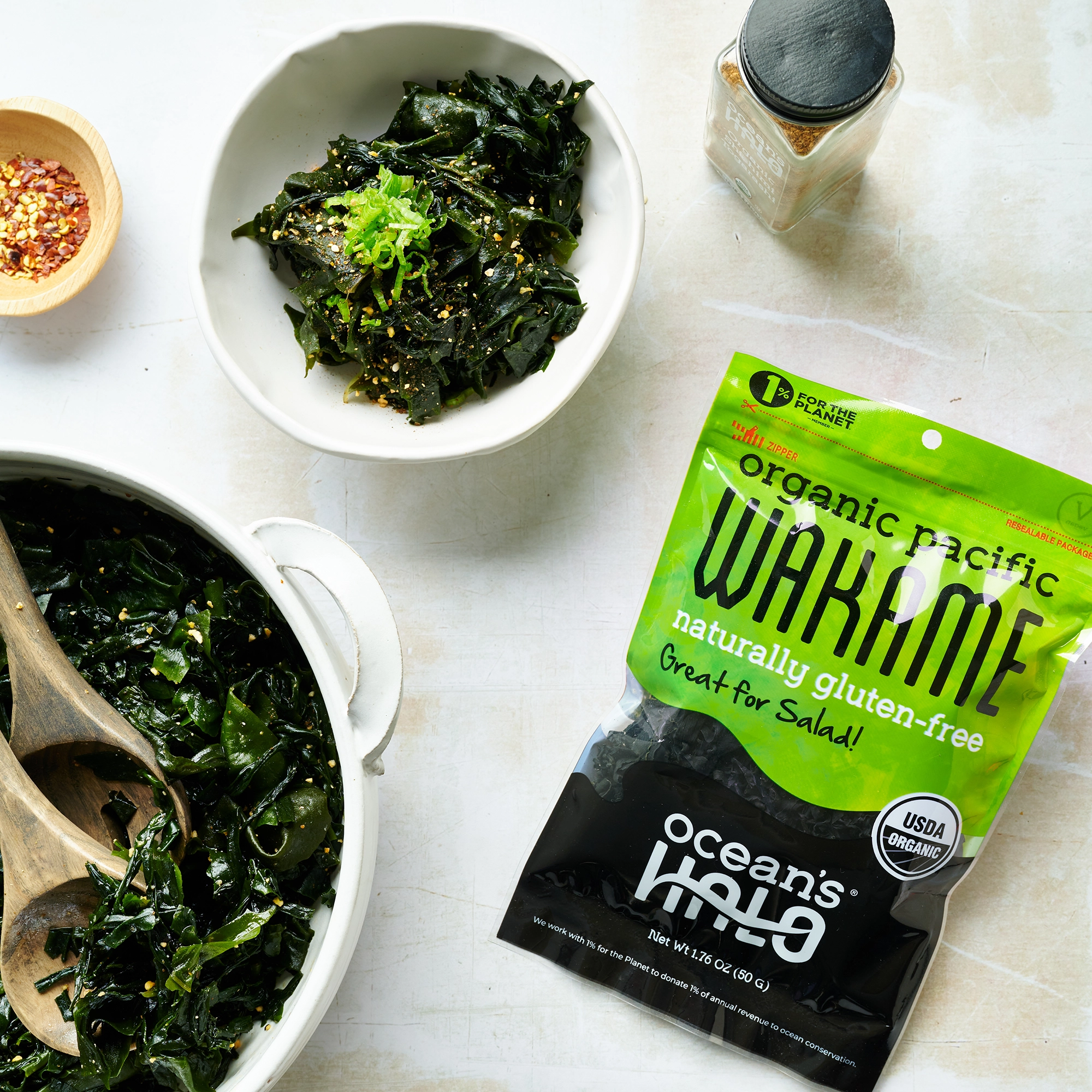 Bowl and serving dish of wakame seaweed salad next to an Ocean's Halo Organic Pacific Wakame bag and spice shaker