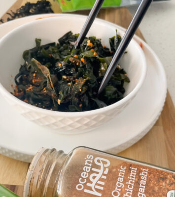 A bowl filled with fresh greens, accompanied by chopsticks and a spoon, ready for a healthy meal.