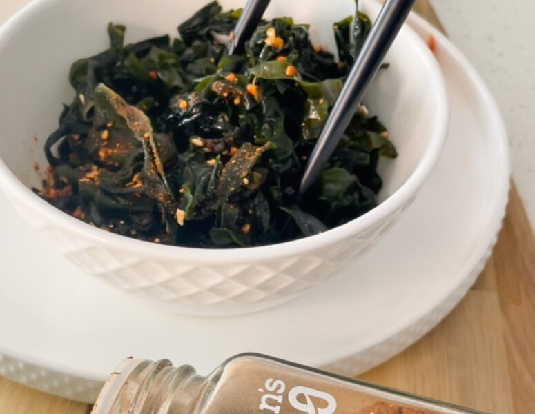A bowl filled with fresh greens, accompanied by chopsticks and a spoon, ready for a healthy meal.