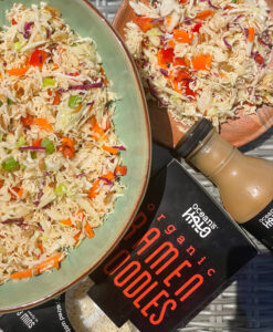 A vibrant organic pak choi salad accompanied by a bottle of sauce, showcasing fresh ingredients and flavors.
