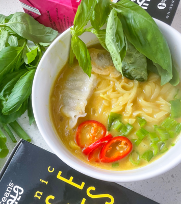 A bowl filled with colorful noodles, fresh vegetables, and aromatic herbs, showcasing a vibrant and healthy meal.