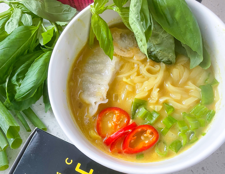 A bowl filled with colorful noodles, fresh vegetables, and aromatic herbs, showcasing a vibrant and healthy meal.