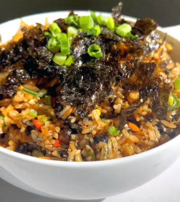 A bowl filled with rice, colorful vegetables, and topped with fresh green onions.