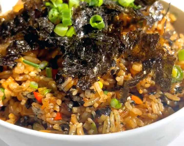 A bowl filled with rice, colorful vegetables, and topped with fresh green onions.