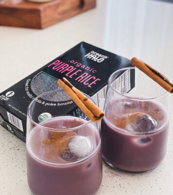 Two glasses filled with purple rice, garnished with cinnamon and accompanied by cinnamon sticks.