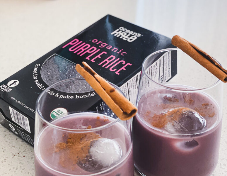 Two glasses filled with purple rice, garnished with cinnamon and accompanied by cinnamon sticks.