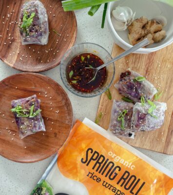 A plate of crispy spicy chicken spring rolls garnished with fresh herbs and served with a dipping sauce.