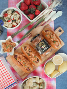 A table set with hot dogs, fresh salad, and various other delicious food items ready for a gathering.