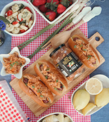 A table set with hot dogs, fresh salad, and various other delicious food items ready for a gathering.