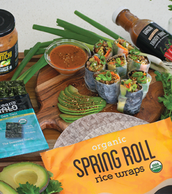 Summer rolls sliced on a cutting board next to Ocean’s Halo Spring roll wraps, dressing, Sea salt seaweed, & Kimchi.