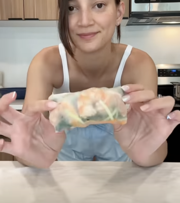 A woman holds a piece of food in her hands, showcasing her delight in the culinary experience