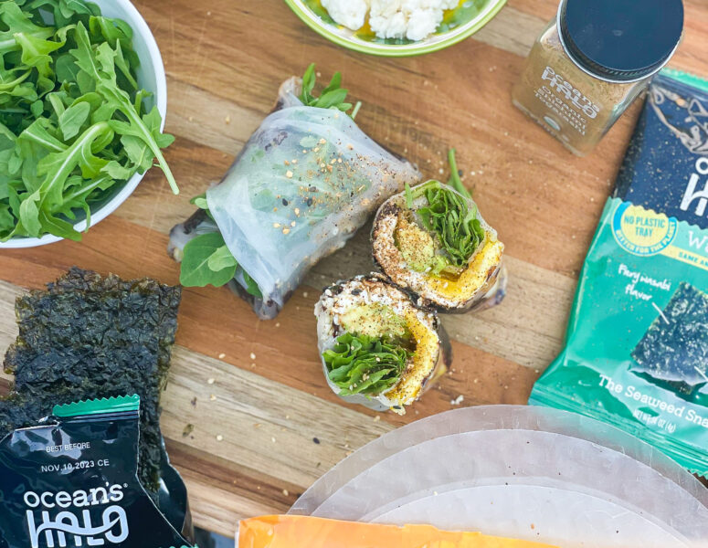 A feta egg breakfast wraps on a cutting board with Ocean’s Halo Spring roll wraps, Wasabi Seaweed and Shichimi Togarashi.