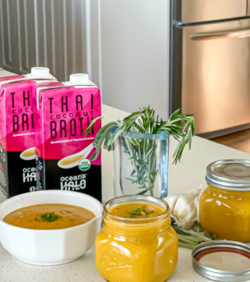 A bowl and a mason jar of Butternut Squash soup with Ocean’s Halo Thai Coconut Soup Broth and fresh rosemary next to it