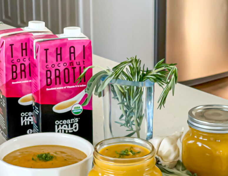 A bowl and a mason jar of Butternut Squash soup with Ocean’s Halo Thai Coconut Soup Broth and fresh rosemary next to it