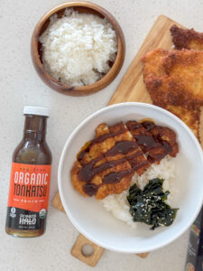 A bowl of Chicken Katsu over rice with Ocean’s Halo Organic Tonkatsu Sauce next to it