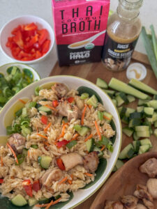 A bowl of Thai Coconut Orzo with Ginger Sesame Chicken with Thai Coconut Broth and Ginger Sesame dressing next to it