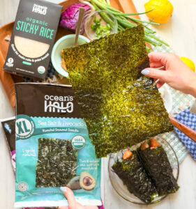 Someone holding a sheet of ocean's halo sea salt and avocado oil XL seaweed snack
