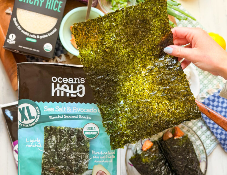 Someone holding a sheet of ocean's halo sea salt and avocado oil XL seaweed snack